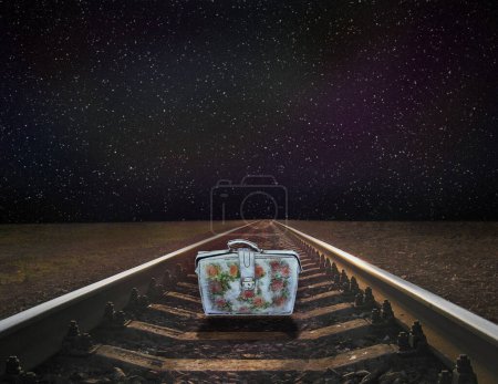 colorful suitcase standing railway rails on background of starry sky. Rails with cosmic landscape. Moody night landscape. traveling mood. lonely suitcase standing on rails. Night view of sky and road