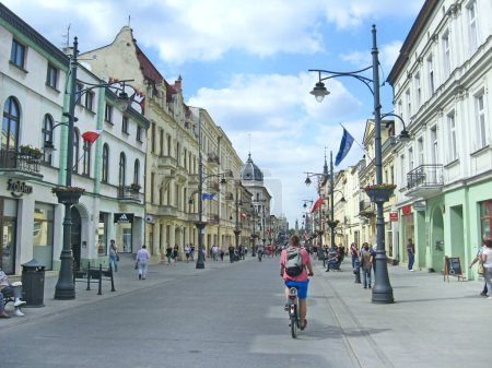 Photo for Lodz - Poland. 27 July 2019: Central street of Lodz decorated with Polish flags. People walking along city street. View of main street of Lodz. People living in the city. Cityscape. Urban panorama - Royalty Free Image