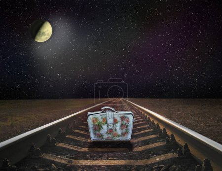 Night railway road. Rails with cosmic landscape. colorful suitcase standing on railway rails on nighty sky. Rails with cosmic landscape. lonely suitcase standing on rails.bright Moon shines from space