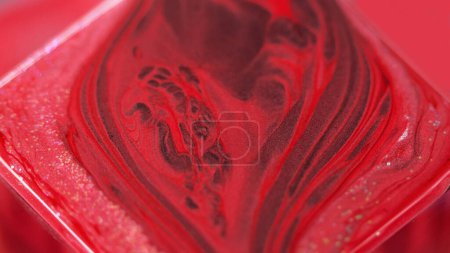 Ink background. Glitter paint. Color fluid mix. Captivating hypnotic macro abstract design red burgundy pigment with sequins stream on square surface in fantasy magic liquid art.