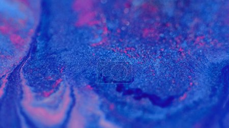 Glitter paint splash. Ink mix. Blur vibrant blue pink color glowing sparkling bokeh light texture emulsion gloss flow abstract art background.