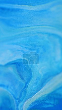 Liquid mix art. Glitter paint flow. Defocused blue silver color sparkling fluid oil texture ink spill emulsion abstract background.
