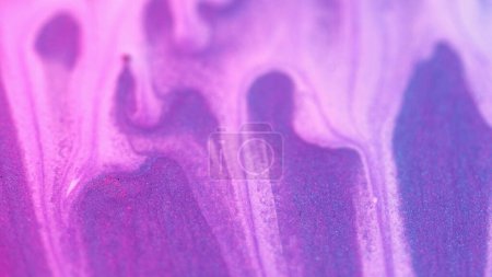 Paint drip. Flowing liquid. Abstract white ink drop flow sparkling motion down at glittered colored purple grained metallic textured background blur.