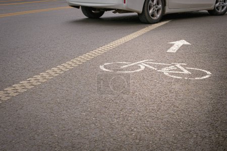 Téléchargez les photos : Un véhicule traversant une piste cyclable marquée par un vélo peint et des symboles de flèche directionnelle. - en image libre de droit