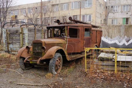 Ein rostiger sowjetischer Oldtimer-LKW steht verlassen vor Industriebauten.