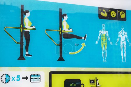 Foto de Primer plano de un colorido panel de infografía sobre equipos de entrenamiento, mostrando instrucciones de ejercicio con reflexiones de edificios urbanos. - Imagen libre de derechos