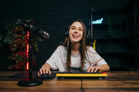 Photo for Happy female gamer with a smile on her face playing online games on the computer at home and watching, looking at the screen with a smile on her face. - Royalty Free Image