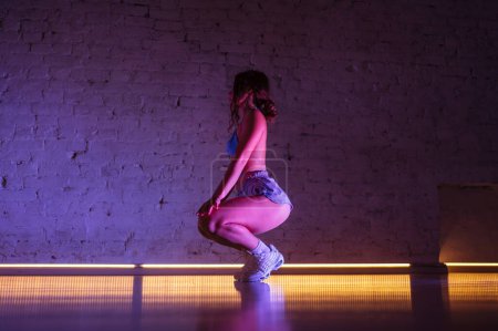 Photo for Attractive female twerk dancer dancing in dance studio in pink light on wall background. - Royalty Free Image