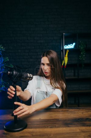 Photo for Attractive female blogger prepares to record a video in the studio, adjusts the microphone before shooting. Portrait of a blogger preparing to do. - Royalty Free Image