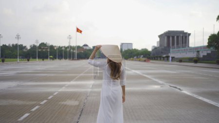 Photo for Portrait of Asian Vietnamese woman with Vietnam dress and straw hat travel at Ho Chi Minh Mausoleum, Tourist attraction landmark in urban city town of Hanoi, Vietnam. People lifestyle. - Royalty Free Image