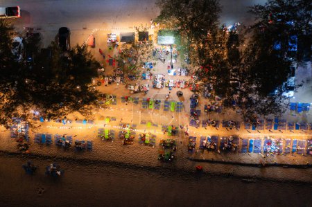 Téléchargez les photos : Vue aérienne de la foule de touristes se relaxant le long de la plage de Pattaya la nuit, Thaïlande. Ombres claires des personnes en vacances. - en image libre de droit