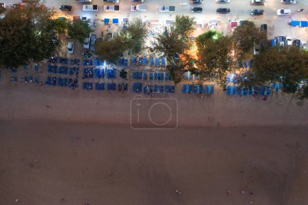 Téléchargez les photos : Vue aérienne de la foule de touristes se relaxant le long de la plage de Pattaya la nuit, Thaïlande. Ombres claires des personnes en vacances. - en image libre de droit