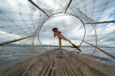 Téléchargez les photos : Pêcheur birman jetant ou jetant un filet pour attraper des poissons d'eau douce dans le lac Unle, rivière naturelle en Asie au Myanmar. Style de vie des gens. - en image libre de droit