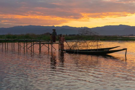 Téléchargez les photos : Pêcheur birman jetant ou jetant un filet pour attraper des poissons d'eau douce dans le lac Unle, rivière naturelle en Asie au Myanmar. Style de vie des gens. - en image libre de droit