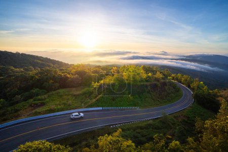 Aerial view of national park Inthanon, cars driving on curved, zigzag curve road or street on mountain hill with green natural forest trees in rural area of Chiang Mai, Thailand.