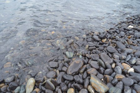 Foto de Granito piedra grava rocas suelo patrón textura de la superficie en el lago de mar. Primer plano del material exterior para el fondo de decoración de diseño. Escombros - Imagen libre de derechos