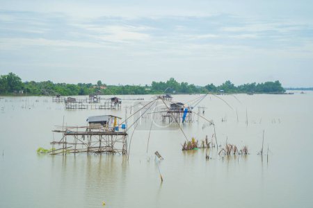 Photo for Fishing trap net in canal with fisherman urban city village town houses, lake or river. Nature landscape fisheries and fishing tools at Pak Pha, Songkhla, Thailand. Aquaculture farming - Royalty Free Image