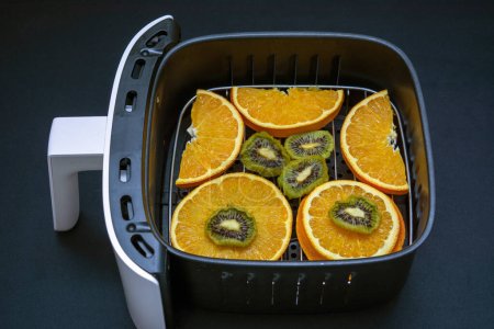 Air fryer with fruits ready to be dehydrated and dried in it.