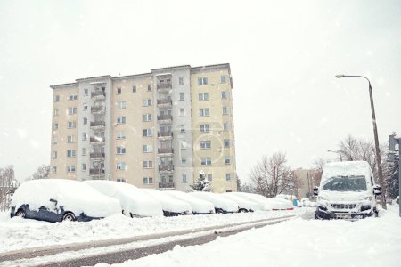 Foto de Una calle en Cracovia está cubierta de nieve después de una ventisca en invierno. Coche enterrado bajo la nieve después de fuertes nevadas - Imagen libre de derechos