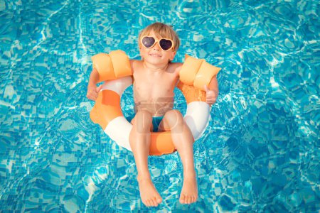 Téléchargez les photos : Joyeux enfant qui s'amuse pendant les vacances d'été. Enfant jouant dans la piscine. Concept de mode de vie sain actif - en image libre de droit
