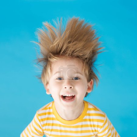 Photo for Happy child shouting against blue paper background. Funny kid hanging upside down. Summer vacation and travel concept - Royalty Free Image