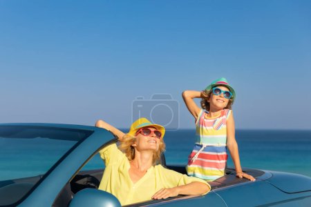 Foto de Feliz viaje familiar en coche en el mar. Madre e hijo divirtiéndose en cabriolet azul. Concepto vacaciones de verano - Imagen libre de derechos