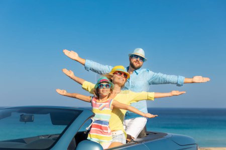Téléchargez les photos : Bonne famille voyage en voiture à la mer. Mère, père et fille s'amusent en bleu cabriolet. Concept vacances d'été - en image libre de droit