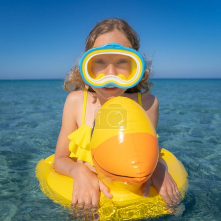 Foto de Un niño divertido en vacaciones de verano. Chica feliz nadando en el mar - Imagen libre de derechos