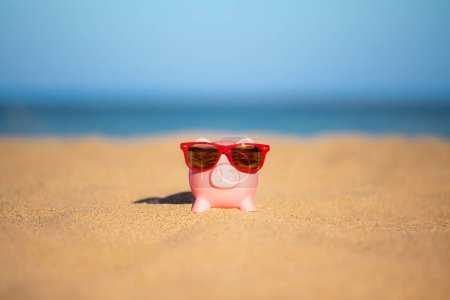 Foto de Piggybank en la playa contra el mar y el cielo de fondo. Ahorro para viajes de verano y concepto de vacaciones - Imagen libre de derechos