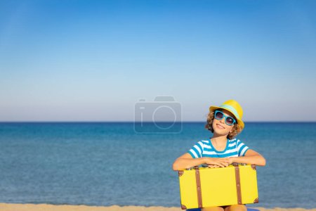 Photo for Child with vintage suitcase on summer vacation. Girl having fun on the beach. Kid sitting against sea and sky background.  Travel and adventure concept - Royalty Free Image