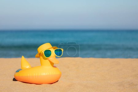 Foto de Divertido pato amarillo con sombrero de playa y gafas de sol contra el mar azul y el fondo del cielo. Vacaciones de verano y concepto de viaje - Imagen libre de derechos