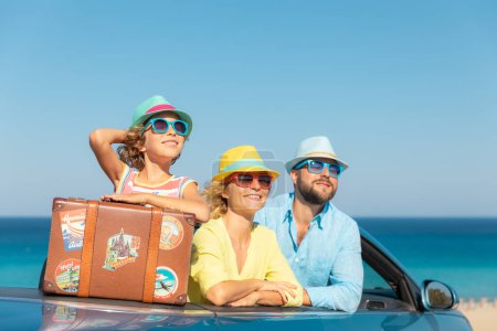 Foto de Feliz viaje familiar en coche en el mar. Madre, padre e hija divirtiéndose en cabriolet azul. Concepto vacaciones de verano - Imagen libre de derechos