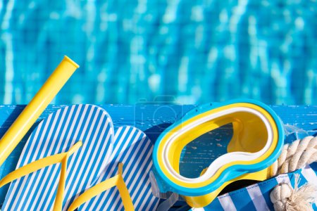 Photo for Beach flip-flops and snorkel mask on blue wood against swimming pool background. Summer vacation and travel concept concept - Royalty Free Image