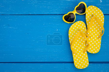 Foto de Chanclas de playa y gafas de sol sobre fondo de madera azul. Concepto de vacaciones de verano y viajes - Imagen libre de derechos