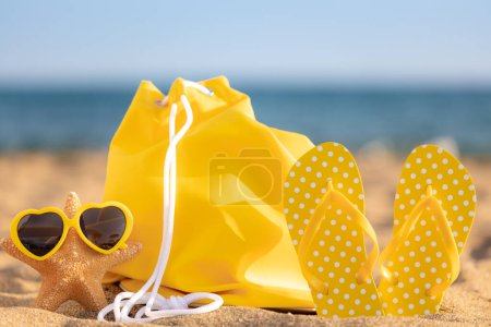 Téléchargez les photos : Tongs de plage sur le sable sur fond de mer et de ciel. Concept vacances d'été - en image libre de droit