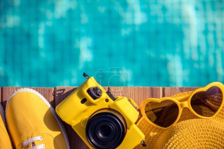 Foto de Zapatillas amarillas y cámara en madera azul sobre fondo de agua. Concepto de vacaciones de verano y viajes - Imagen libre de derechos