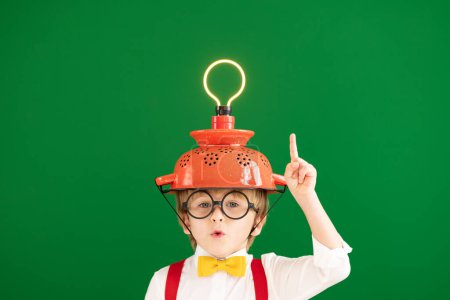 Photo for Smart child in the class against blackboard. Funny kid with lightbulb at school. Education, start up and business idea concept - Royalty Free Image