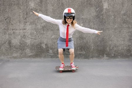 Téléchargez les photos : Heureuse femme d'affaires en skateboard. Portrait extérieur de jeune femme. Retour au travail, démarrage et concept d'idée d'entreprise - en image libre de droit