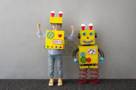 Foto de Niño feliz con robot. Un chico gracioso tiene una idea. Concepto de éxito, tecnología creativa e innovación - Imagen libre de derechos