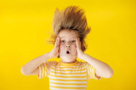 Photo for Surprised child holding face. Shocked kid against yellow background. Boy wearing striped shirt. Summer vacation and travel concept - Royalty Free Image