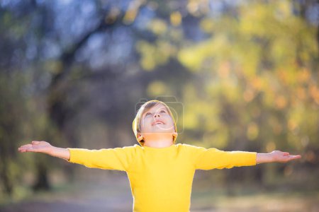 Foto de Retrato de niño feliz sobre fondo de hojas amarillas. Niño sonriente divirtiéndose al aire libre en el parque de otoño. Concepto libertad e imaginación - Imagen libre de derechos
