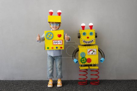 Téléchargez les photos : Enfant heureux avec robot. Un gamin drôle a une idée. Succès, créativité et innovation concept technologique - en image libre de droit