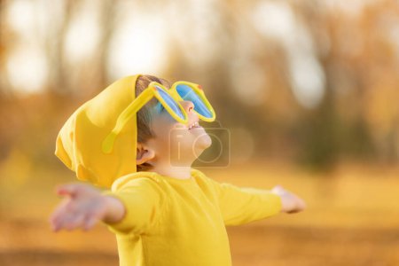 Téléchargez les photos : Portrait d'enfant heureux sur fond de feuilles jaunes. Enfant souriant s'amusant en plein air dans le parc d'automne. Concept de liberté et d'imagination - en image libre de droit