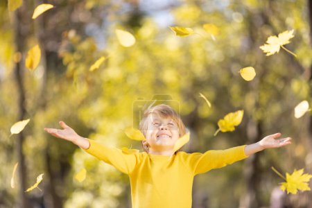 Photo for Happy child throw up yellow leaves. Smiling kid having fun outdoor in autumn park. Freedom and imagination concept - Royalty Free Image