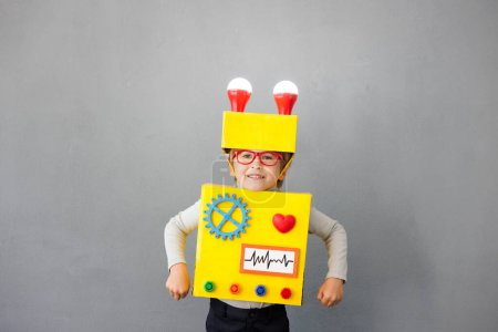 Foto de Un niño feliz con un robot. Un chico gracioso tiene una idea. Concepto de éxito, tecnología creativa e innovación - Imagen libre de derechos