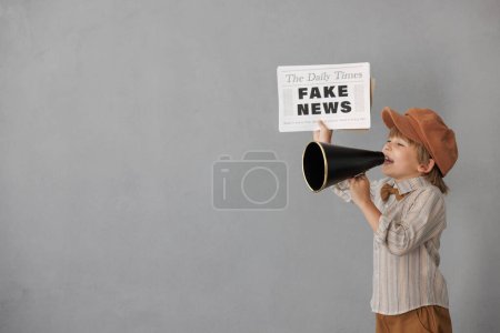 Newsboy schreit durch Lautsprecher vor Grunge-Hintergrund. Junge verkauft Fake News. Kind im Vintage-Kostüm. Kind hält Zeitung. Soziales Medien- und Internet-Konzept