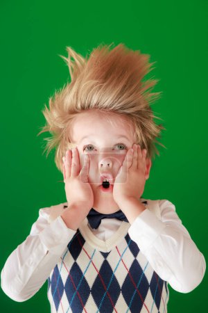 Photo for Surprised child in class. Funny kid against green chalkboard background. Back to school and education concept - Royalty Free Image