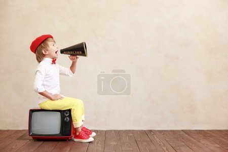 Photo for Newsboy shouting through loudspeaker against grunge wall background. Kid selling newspaper. Child wearing vintage costume. Social media and Internet nerwork concept - Royalty Free Image
