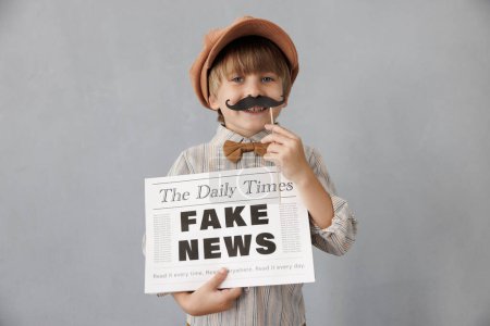 Newsboy shouting against grunge wall background. Boy selling fake news. Child wearing vintage costume. Kid holding newspaper. Social media and Internet nerwork concept