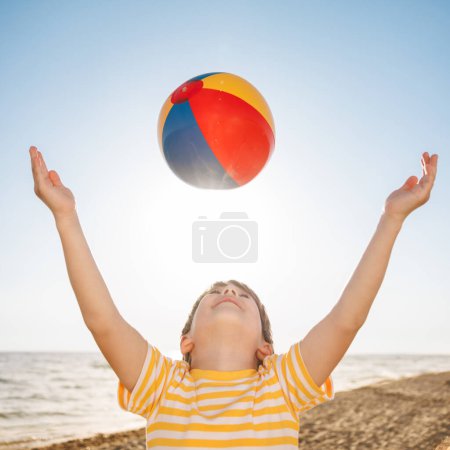 Téléchargez les photos : Joyeux enfant en vacances d'été. Un gamin qui s'amuse sur la plage. Garçon jouant au beach ball. Vacances d'été et concept de voyage - en image libre de droit